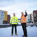 Seppo Saaristo ja Anders Eklund seisovat lumisella pihalla kerrostalojen edessä