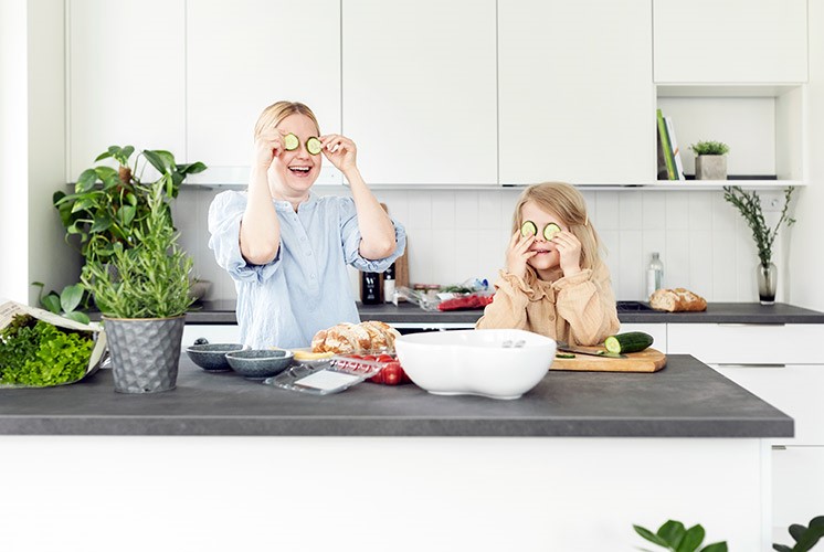 Äiti ja lapsi laittavat ruokaa skandinaavisessa vaaleassa keittiössä.
