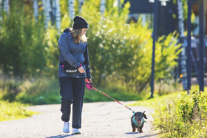 Nainen ulkoiluttamassa koiraa Painiityn alueella