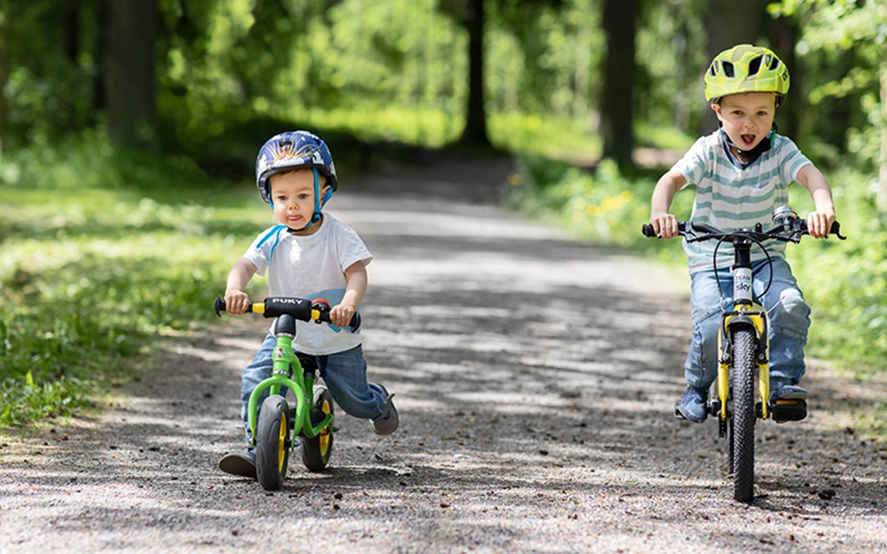 Lapset pyöräilevät luontopolulla kesäisessä säässä.